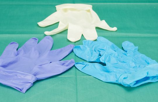 Three pieces of latex medical gloves placed on green fabric.