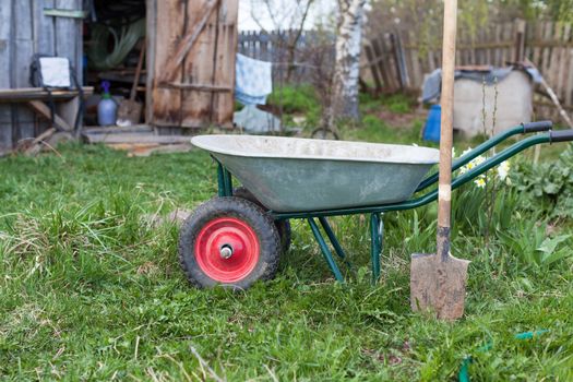 Shovel and the cart on a garden site with flowers