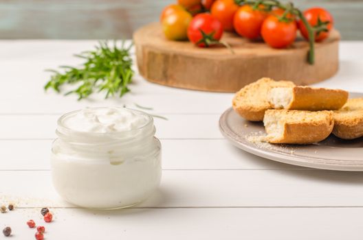 Organic cherry tomatoes with rosemary, swedish toasts and cream cheese on rustic wooden table