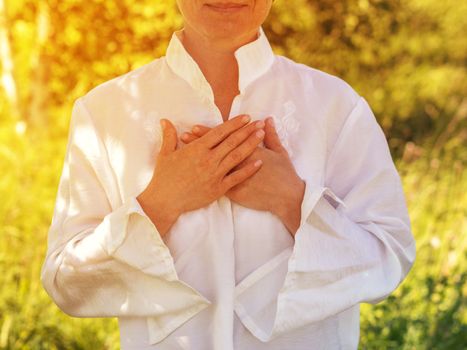 Women's hands on heart in meditating outdoors