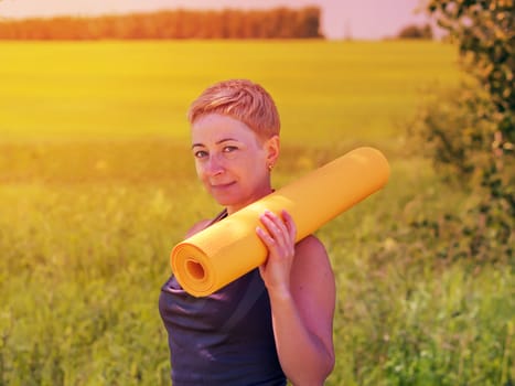 Mature Woman Holding Rolled Up Exercise Mat Outdoors