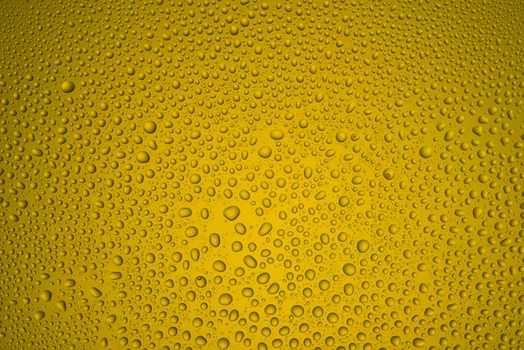 Background from drops of water of the different size on yellow glass