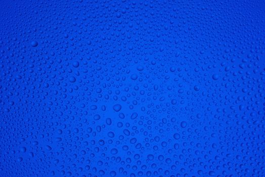 Background from drops of water of the different size on blue glass