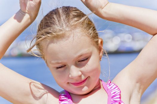 Portrait of dancing girl on the riverbank in pink swimsuit