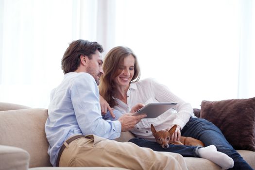 Cheerful couple using digital tablet at home