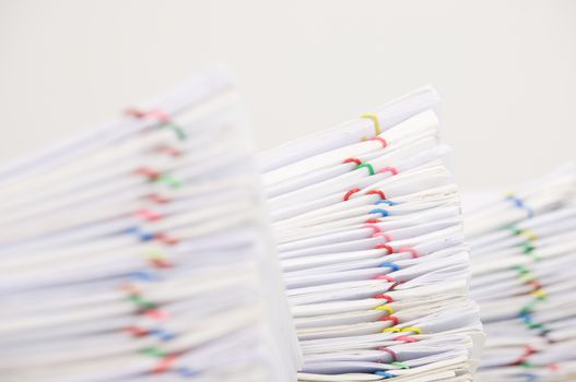 Pile overload document of report with colorful paperclip have blur pile overload paperwork as foreground and background with white background.