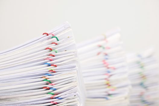 Pile overload document of report with colorful paperclip have blur pile overload paperwork as background with white background.