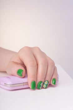 Female left hand with green manicure on a white table