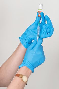 Hands in rubber gloves gather medicine in the syringe from a bottle