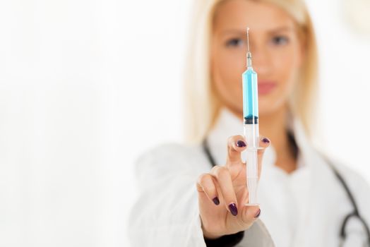 Close-up injections with blue liquid, in the hands of a pretty blonde nurse with a face out of focus.