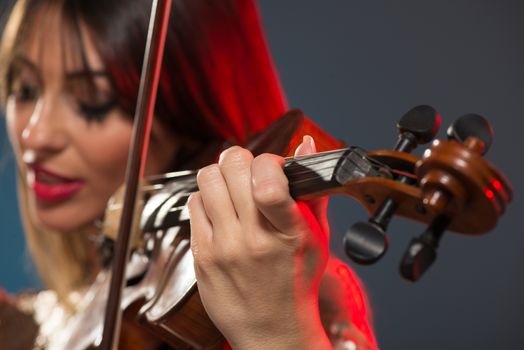 Close-up of a violin played by a young woman with a face out of focus.