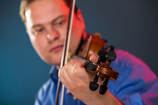 Close-up of violin in the hands of the violin virtuoso with a face out of focus.