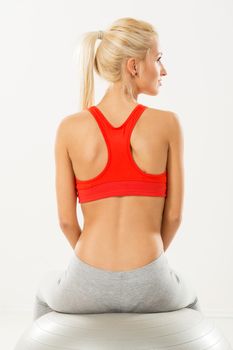 Cute sporty Young girl sitting to pilates ball and resting. Rear view.