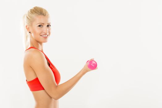 Cute sporty Young girl exercising with dumbbells. Looking at camera.