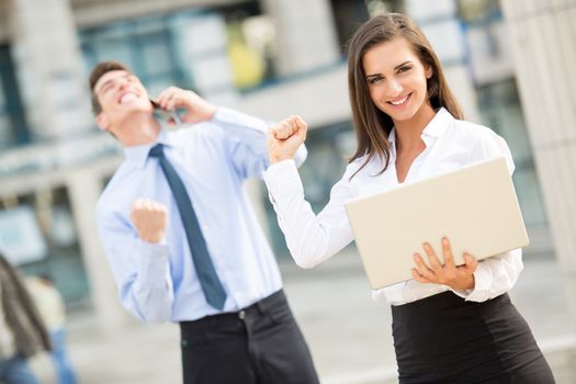 Young business couple standing in front of office buildings caught in the moment of joy for the successful completion of the job.