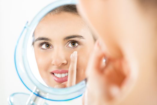 Photography of reflection in the mirror, beautiful girl who applied the cream on her face.