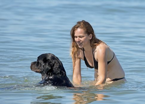 woman and rottweiler playing in the sea