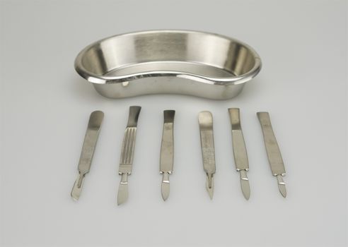 Many types of scalpel with kidney shape bowl on white background.