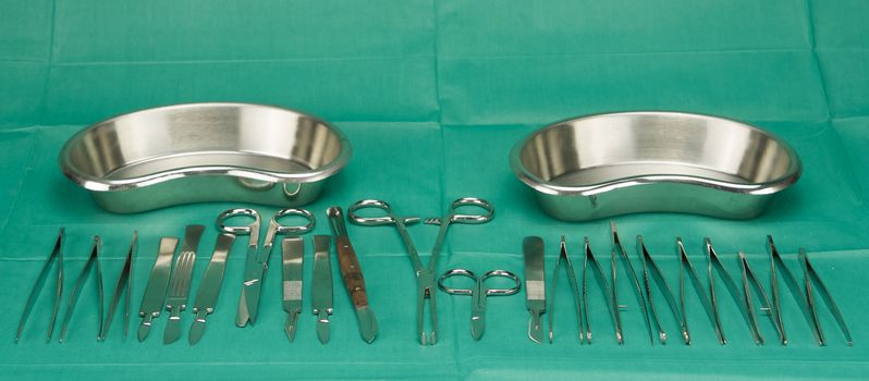 Medical instruments  and kidney shape bowl were put on green fabric