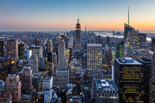New York City. Manhattan downtown skyline with illuminated Empire State Building and skyscrapers at dusk.