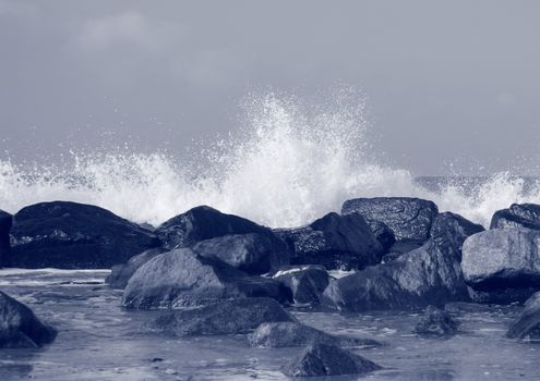 Black rocks protecting coast against crashing white waves