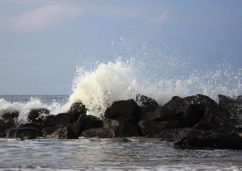 Crashing waves against black rocks at coast