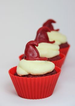 Isolated row of red velvet cupcakes with cream cheese frosting
