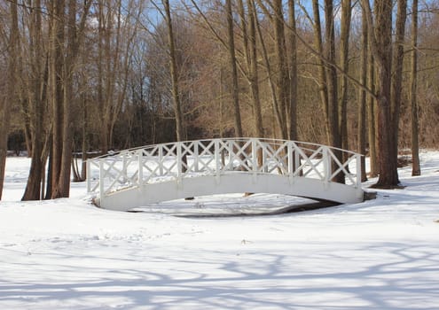 Wooden white bridge over snowy frozen water