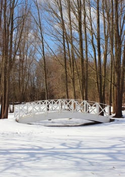 Wooden white bridge over snowy frozen water