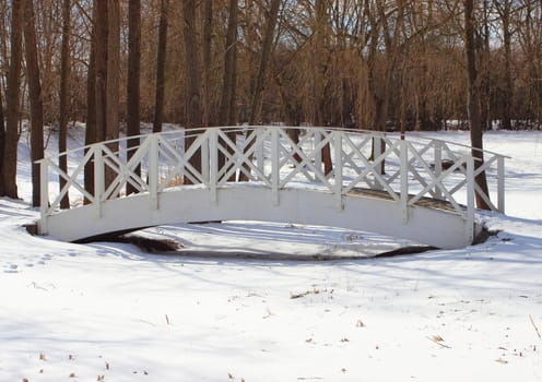 Wooden white bridge over snowy frozen water