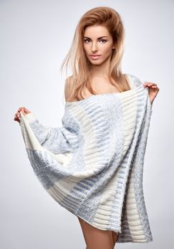 Beauty fashion portrait woman in stylish warm knitted sweater. Sensual attractive pretty blonde sexy model girl, shiny straight hair, confidence. Unusual creative provocative. Emotional playful people