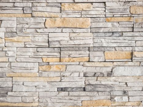 a wall from an artificial gray stone facade with rough fractured surfaces as background