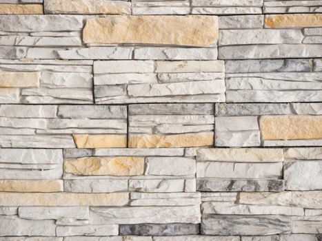 a wall from an artificial gray stone facade with rough fractured surfaces as background