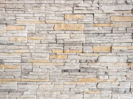 a wall from an artificial gray stone facade with rough fractured surfaces as background