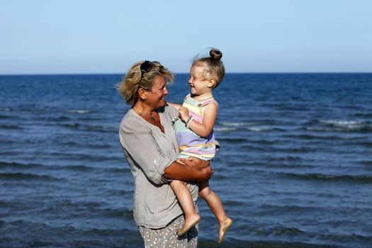 Grandmother with a little granddaughter on the beach