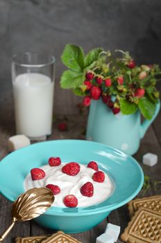 Strawberry with cream in a ceramic Cup, cookies and milk in glass on old wooden surface. Bouquet with strawberries in a ceramic vase and antique spoon In a rustic style.