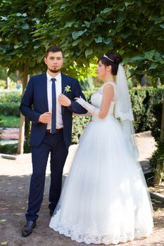 Happy smiling newlyweds walking outdoors, kissing and embracing on their wedding day