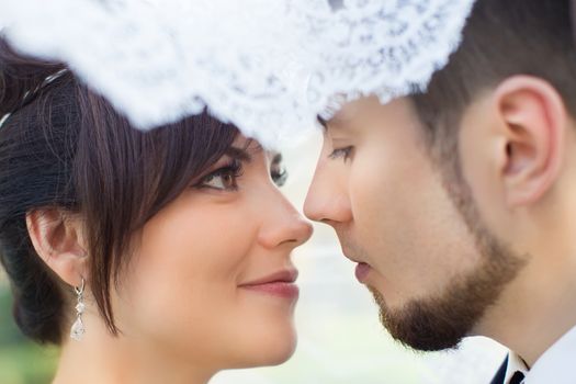 Happy smiling newlyweds walking outdoors, kissing and embracing on their wedding day