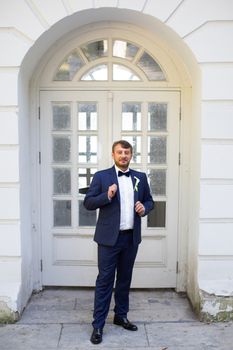 Happy handsome smiling groom in black suit with boutonniere
