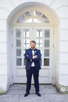 Happy handsome smiling groom in black suit with boutonniere