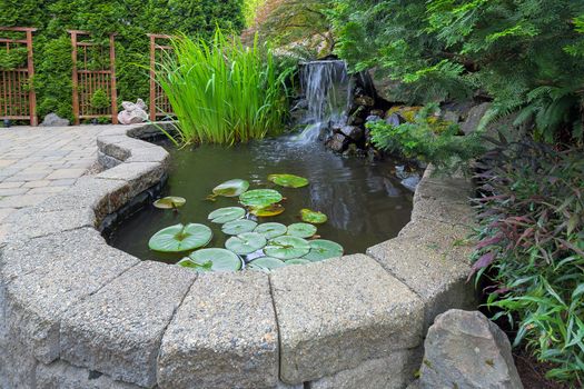 Garden Backyard pond with waterfall water plants brick paver patio trellis landscaping