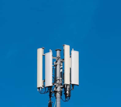 closeup of cellular antenna between trees on blue sky