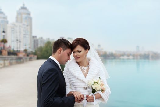 groom gently touched to the bride on a pier near the sea