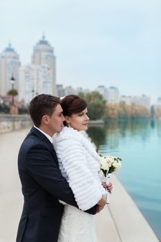 groom gently touched to the bride on a pier near the sea