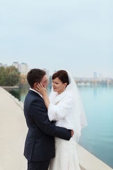 groom gently touched to the bride on a pier near the sea