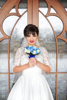 Bride holding bouquet, smiling at the camera on a rainy day