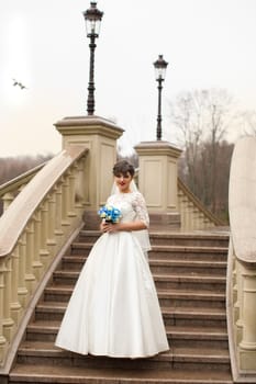 Bride holding bouquet, smiling at the camera on a rainy day