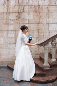 Bride holding bouquet, smiling at the camera on a rainy day