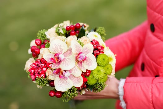 Stylish rich bouquet with berries in hands of the girl