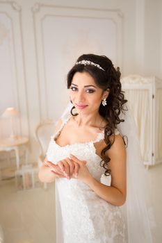 beautiful brunette bride in a luxurious wedding dress posing in interior